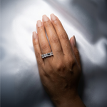 18K solid gold emerald cut diamond eternity band on hand with satin backdrop